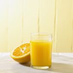 Halve sinaasappel en glas geperste jus